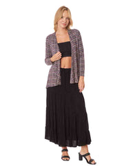 Woman wearing a black top and long black skirt with a patterned cardigan 
