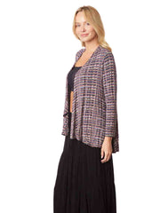 Woman wearing a black top and long black skirt with a patterned cardigan 
